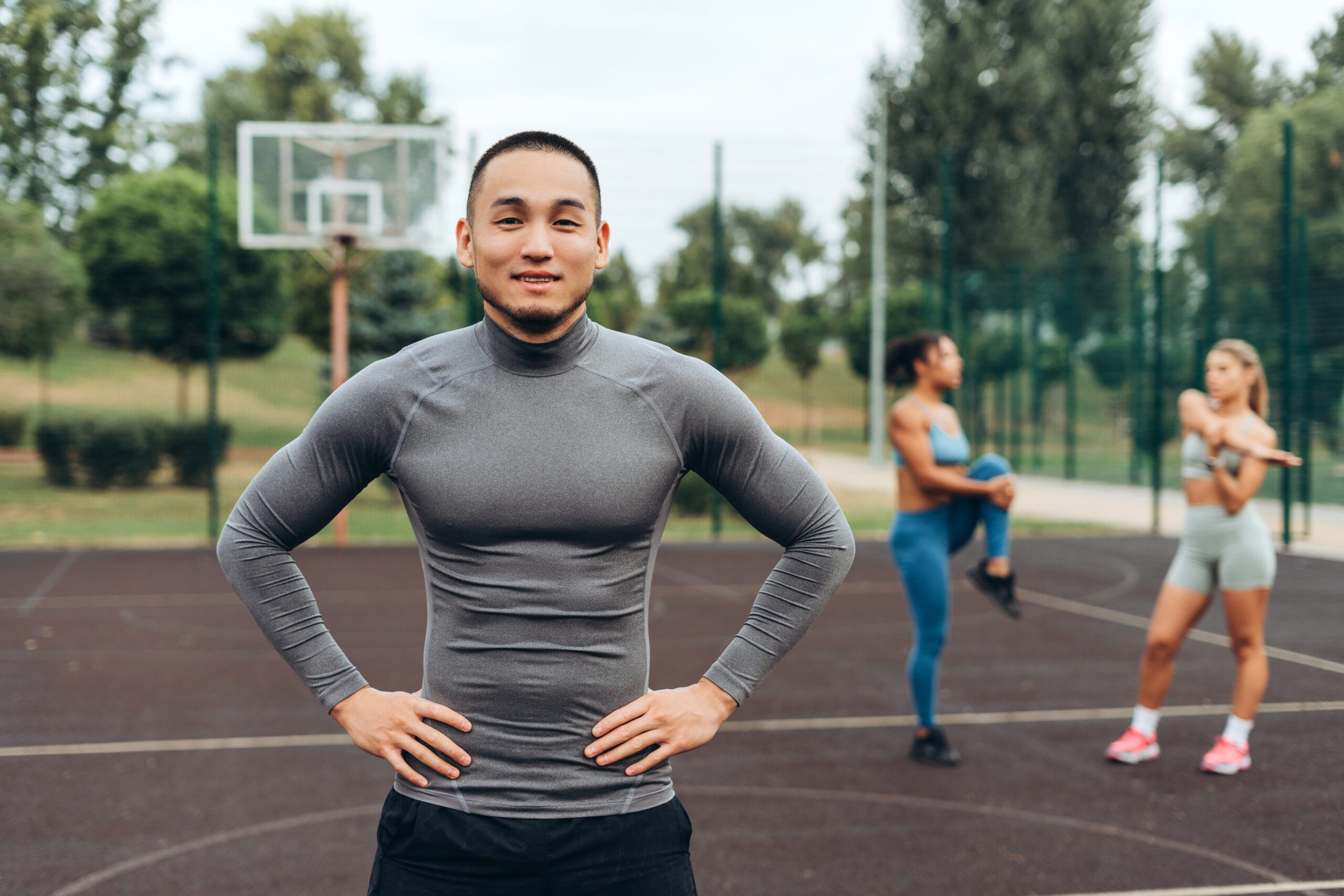 Portrait of handsome Asian athlete wearing sportwear, posing on the street, looking at camera